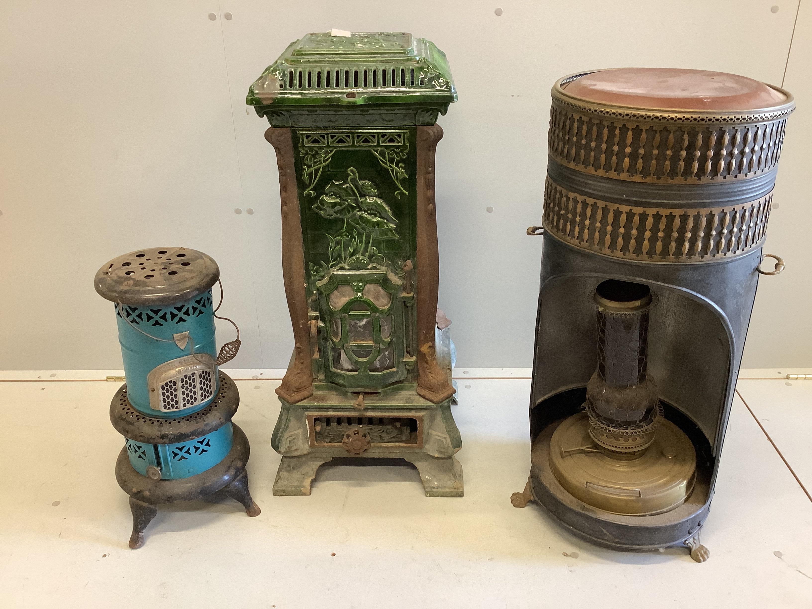 An early 20th century French enamelled cast iron heater, height 88cm and two other circular paraffin heaters